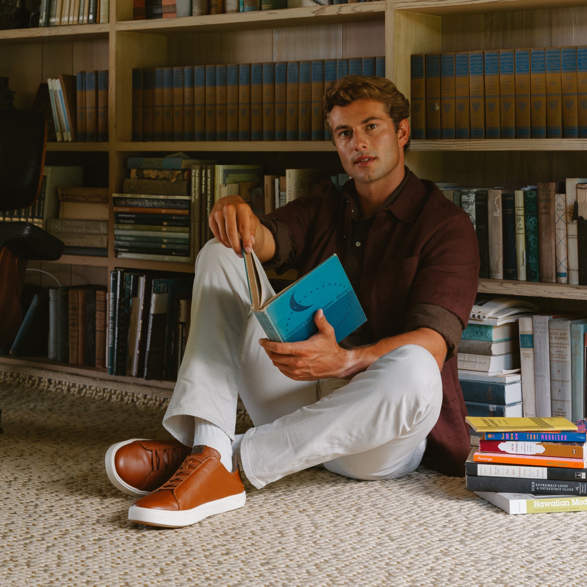 Man wearing dark brown button-up shirt and white pants with cognac leather sneaker with white sole.